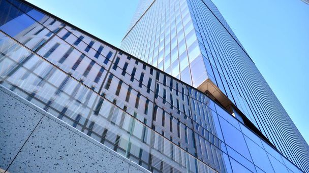 青い空の建物のガラスのファサード。ビジネス街の中心部にある高層ビル現代的なガラスの建物の背景.  - 写真・画像