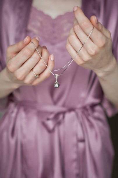 An elegant small necklace in the hands of a girl. - Fotografie, Obrázek