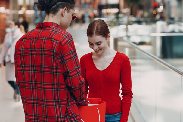 Sevgililer Günü 'nde bir adam sevgilisine kalp şeklinde bir kutu veriyor. Alışveriş merkezindeki genç çift.. - Fotoğraf, Görsel