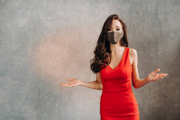 Glamorous girl in a red dress and a protective mask on a vintage background. - Foto, Imagem