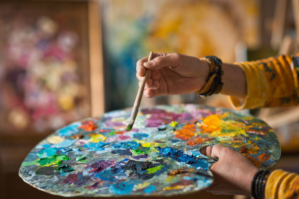 The artist holds a palette in her hand and mixes colors. - Foto, imagen