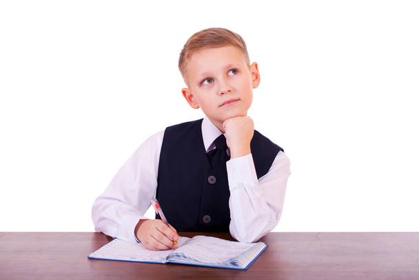 Caucasian school boy at his desk on white background with copy space - bored student boy reading book or textbook  - Foto, Bild