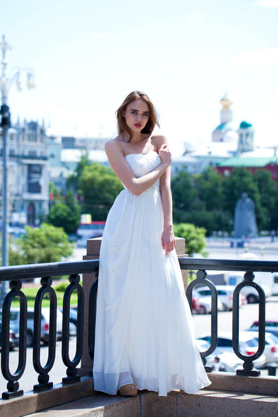 Full length portrait of beautiful model woman with long legs wearing white dress posing summer street - Photo, Image