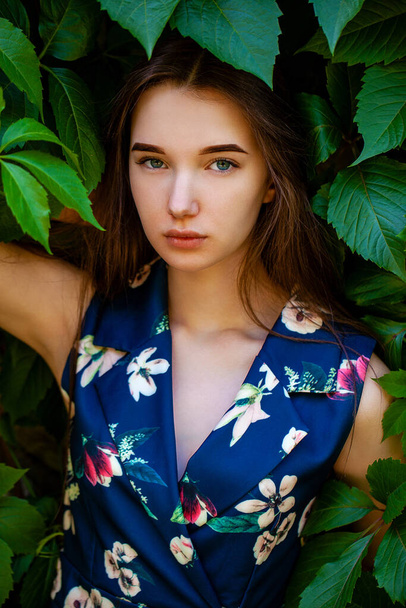 Teenager girl in blue flowers dress on green ivy background - Foto, Imagen
