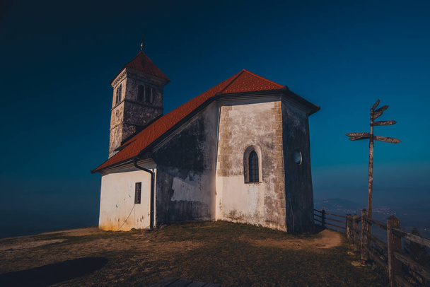 Blick auf die Kirche der Hl. Ana oder Sveta Ana auf einem kleinen Hügel über Podpec, Slowenien an einem sonnigen Wintertag. Malerische Kirche auf einem Aussichtspunkt oder Aussichtspunkt mit toller Aussicht - Foto, Bild