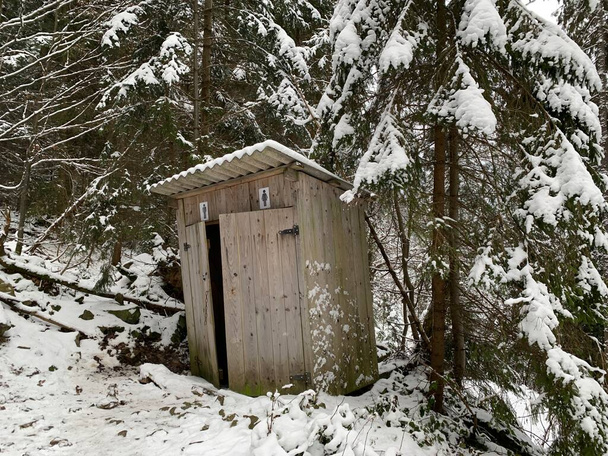 Maalaisvessa talvella ulkona. Puinen rakenne ulkokäymälään. Mökki - Vessa metsässä lumessa. - Valokuva, kuva