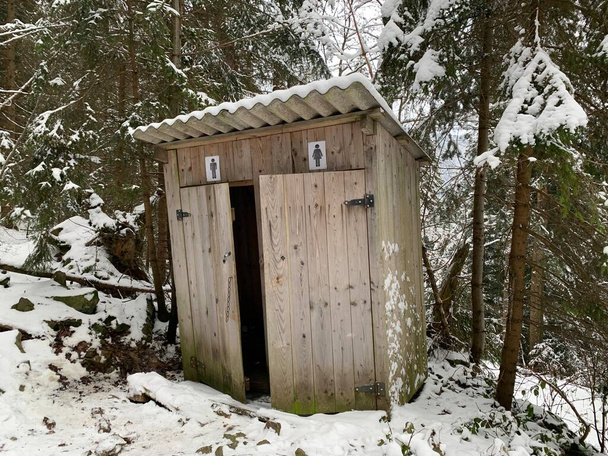 冬の屋外でカントリートイレ。屋外トイレのための木造建築。キャビン-雪の上の森の中のトイレ. - 写真・画像