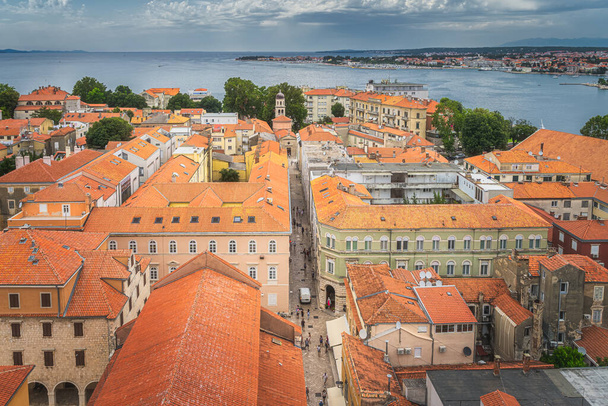 オレンジの瓦屋根とザダル旧市街の狭い石の路地にドローンや鳥の目のビュー。アドリア海、クロアチアの湾と海岸線 - 写真・画像