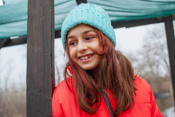 Nehrin arka planında kışın giyinmiş bir kız. Kız 10 yaşında. Turuncu ceketli genç. - Fotoğraf, Görsel