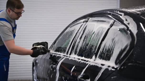 Férfi kéz fekete kesztyűben mossa oldalsó tükör egy fekete autó. - Felvétel, videó