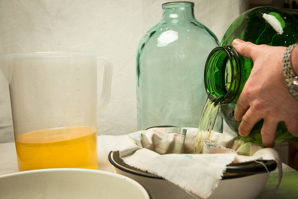 L'homme égoutte et filtre l'alcool infusé de zeste de citron. Le maître mesure le volume de liquide requis pour le mélange avec le sirop de sucre. - Photo, image