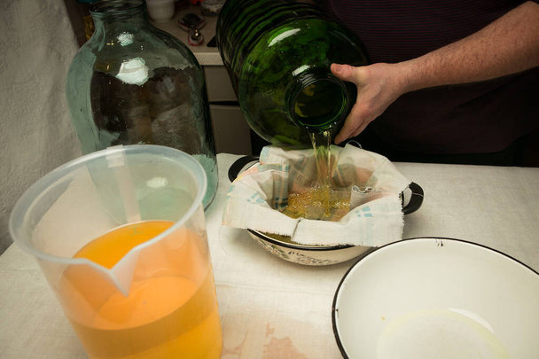 El hombre drena y tensa el alcohol infundido con cáscara de limón. El maestro mide el volumen requerido de líquido para mezclar con el jarabe de azúcar. - Foto, imagen