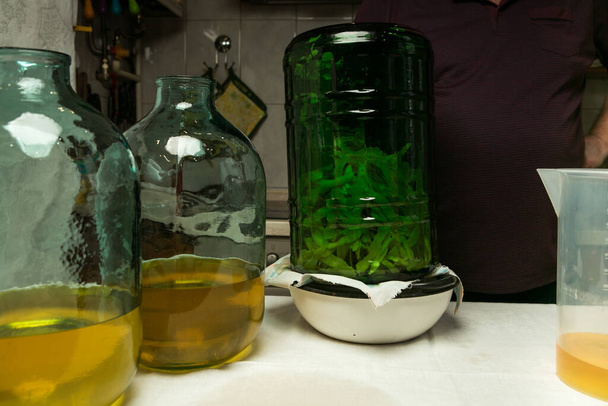 La filtración de la infusión alcohólica en los extremos de la ralladura de limón. Dos botellas de diez litros se llenan con la cantidad correcta de alcohol infundido con ralladura de limón. - Foto, imagen