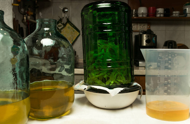 La filtration de l'infusion alcoolique sur le zeste de citron se termine. Deux bouteilles de dix litres sont remplies de la bonne quantité d'alcool infusée de zeste de citron. - Photo, image