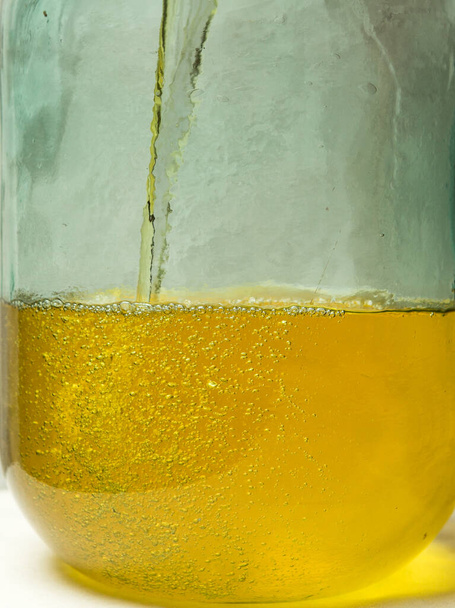 El proceso de hacer licor de limón limoncello en casa. El alcohol infundido con ralladura de limón se vierte en una botella de vidrio de diez litros. - Foto, imagen