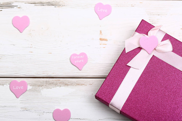 Valentine day design. Pink gift box with bow on white wooden background - Foto, imagen