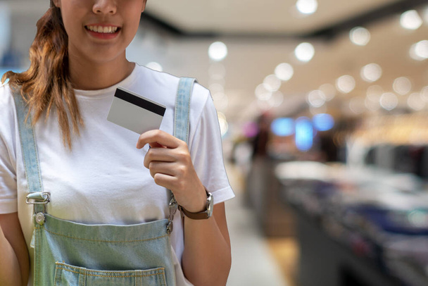 Vonzó vidám fiatal nő kezében hitelkártya a bevásárlóközpont hátterében. Életmód vásárlási koncepció. - Fotó, kép