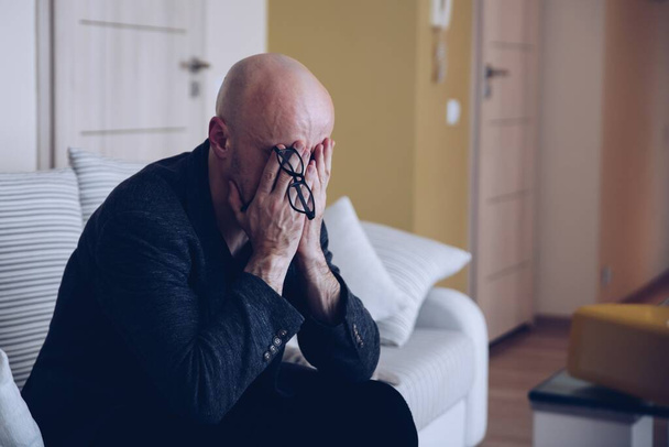 Депрессивный взрослый мужчина сидит на диване. Человек в депрессии. - Фото, изображение