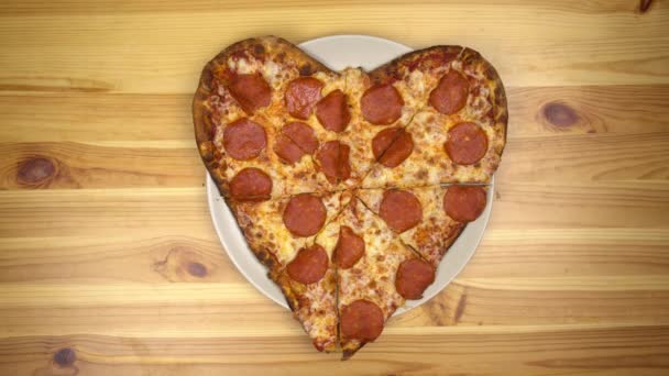 Pizza en forma de corazón para San Valentín. Joven toma una rebanada de pizza vista superior. - Imágenes, Vídeo