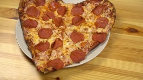 Pizza em forma de coração para o dia dos namorados. Jovem leva uma fatia de pizza. - Filmagem, Vídeo