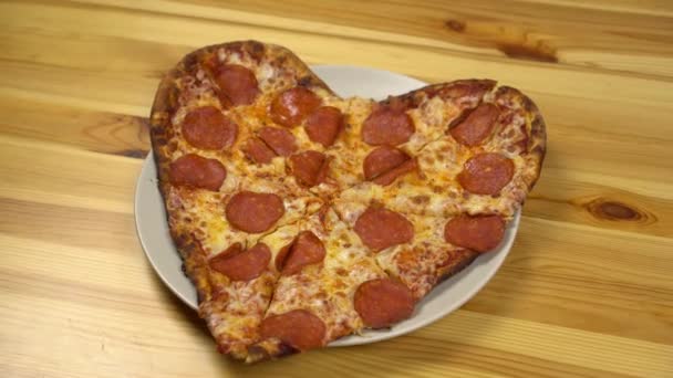 Sevgililer Günü için kalp şeklinde pizza. Genç bayan bir dilim pizza alıyor.. - Video, Çekim
