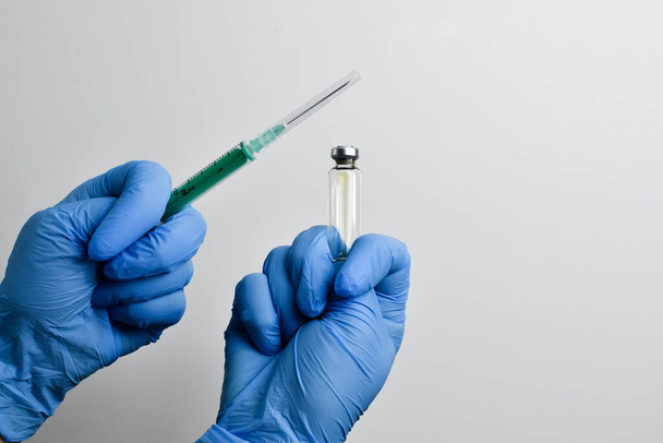 The anti-vaccine protects against the vaccine. A hand in a blue glove shows a fig on a white background. - Foto, Imagen