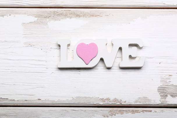 Valentine day love concept. Wooden white lettering love with pink heart on white wooden background - Fotó, kép