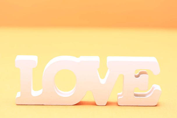 Walentynkowa koncepcja miłości. Słowo miłość wykonane z drewnianych liter na żółtym tle papieru - Zdjęcie, obraz