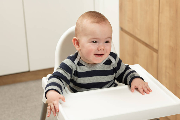 Pequeño bebé sentado en una silla y listo para comer y buscando a mamá - Foto, imagen