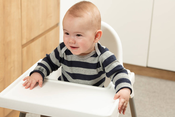 Happy Baby Sitting in High Chair in a White Kitchen - Fotografie, Obrázek