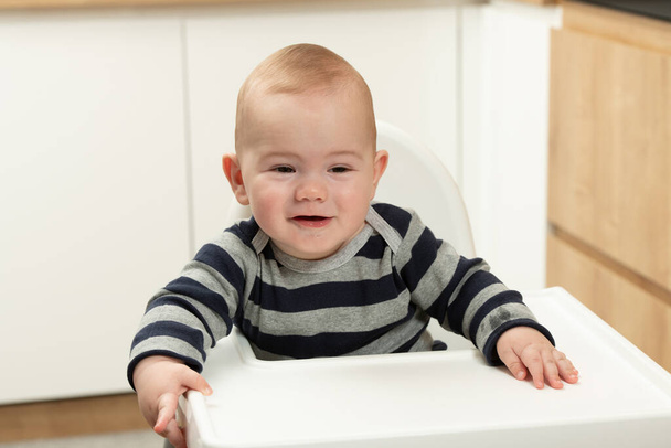 Πορτρέτο ενός χαρούμενου μωρού που κάθεται σε μια ψηλή καρέκλα - Φωτογραφία, εικόνα