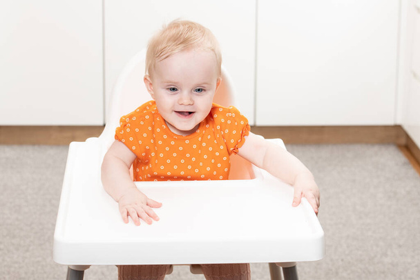 Portrait of a Joyful Baby Sitting on a High Chair - 写真・画像