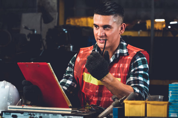 Trabajador de fábrica hablando por radio portátil mientras inspecciona piezas de maquinaria - Foto, Imagen