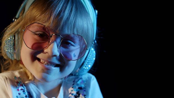 Elégant enfant branché dans les lunettes de soleil à disco party cyberpunk club regardant la caméra et souriant - Photo, image