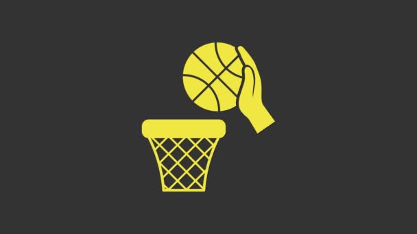 Mano amarilla con pelota de baloncesto e icono de canasta aislada sobre fondo gris. Pelota en el aro de baloncesto. Animación gráfica de vídeo 4K - Metraje, vídeo