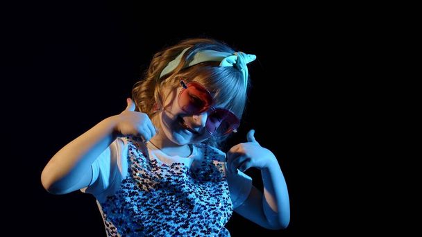 Fashion, prachtig meisje dansen alleen, tonen duimen omhoog in futuristische nachtclub met neon lichten - Foto, afbeelding