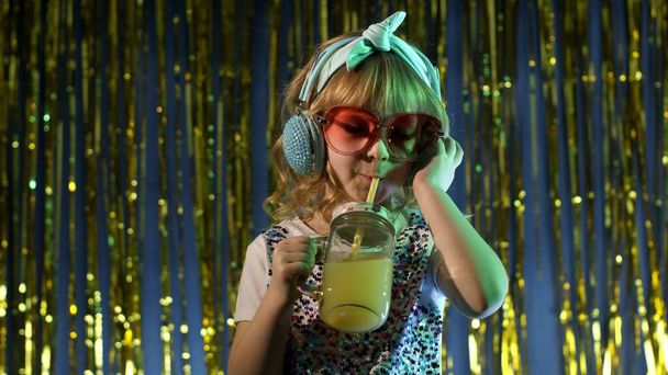 Futuristica ragazza hipster con succo di frutta all'ananas che ascolta musica in cuffia, danza - Foto, immagini