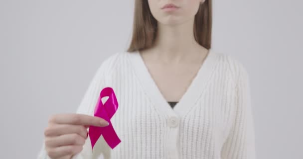 pink ribbon in the hands of a fragile girl as an international symbol of the fight against breast cancer - Footage, Video