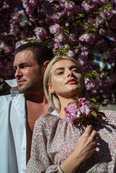 Sensual woman and man in pink flowers in summer blossom park. - Foto, Bild