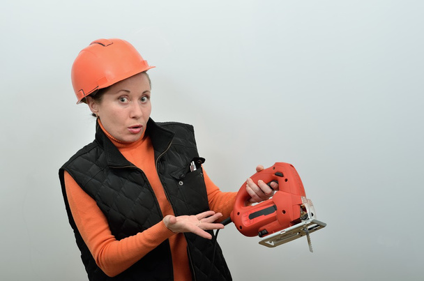 pracownik budowlany kobieta jest zaskoczony, nie wiedząc, jak postępować z narzędzie jig saw - Zdjęcie, obraz