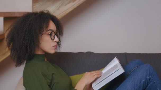 Portrait de profil de jeune femme afro-américaine dans des lunettes livre de lecture et de réflexion, vue de côté, ralenti - Séquence, vidéo
