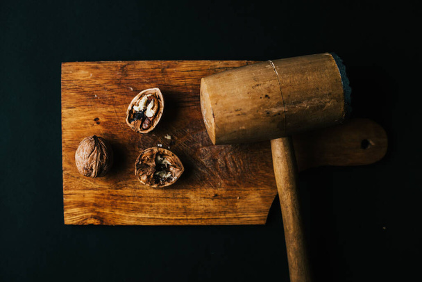 A top view of walnuts with a hammer on a wooden board - Fotó, kép