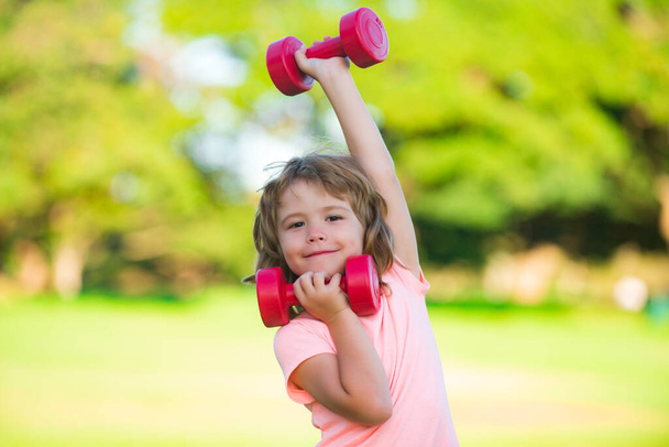 Sport child with dumbbell. Kids sport. Boy exercising in park. Active, healthy lifestyle. - 写真・画像