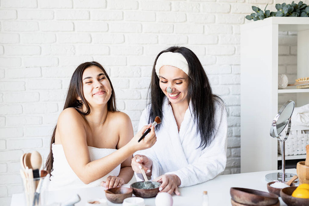 twee mooie vrouwen maken gezichtsmasker hebben plezier - Foto, afbeelding