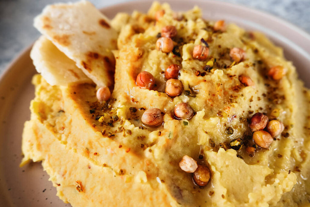 chickpea hummus with olive oil, garlic, spices and sprinkled with fried chickpeas, simple recipes for cooking at home, close up, selective focus - Foto, imagen