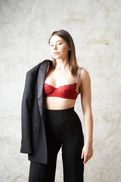 Beauty young brunette wearing black casual suit and red bra posing at apartments interior - Φωτογραφία, εικόνα