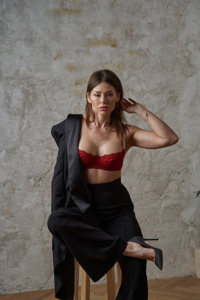Beauty young brunette wearing black casual suit and red bra posing at apartments interior - Valokuva, kuva