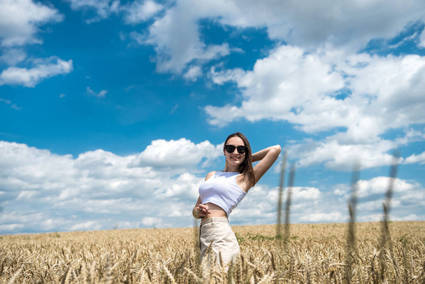 Porträt eines hübschen Mädchens posiert auf dem Hintergrund eines landwirtschaftlichen Feld Sommerzeit - Foto, Bild