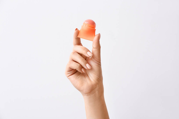 Female hand with natural lip balm on light background - Foto, Imagen