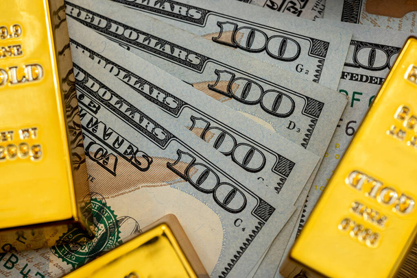 Goud op stapel ons dollarbiljetten als achtergrond. financierings- en spaarconcept - Foto, afbeelding